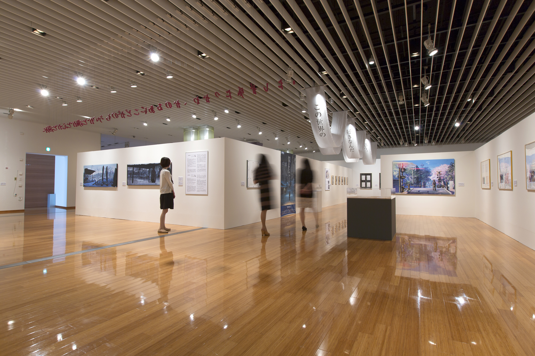 2014年に開催された、展覧会「新海誠展―きみはこの世界の、はんぶん。―」天井からことばをぶらさげたり、布にことばを映したり。さまざまなアイデアで展示している。